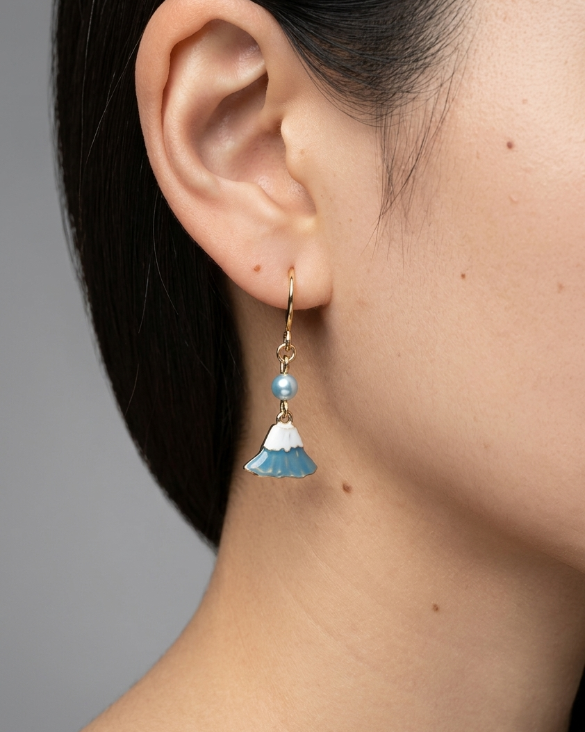 Model wearing pair of gold earring with charm of mt fuji and light blue pearl