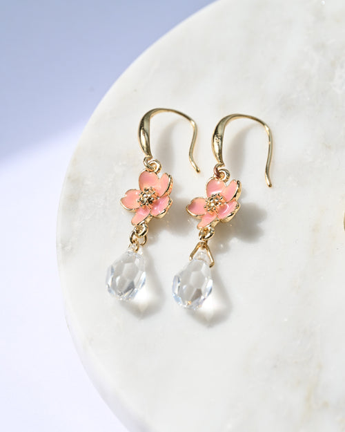 Pair of earrings with pink Sakura charm and clear beads on a light background