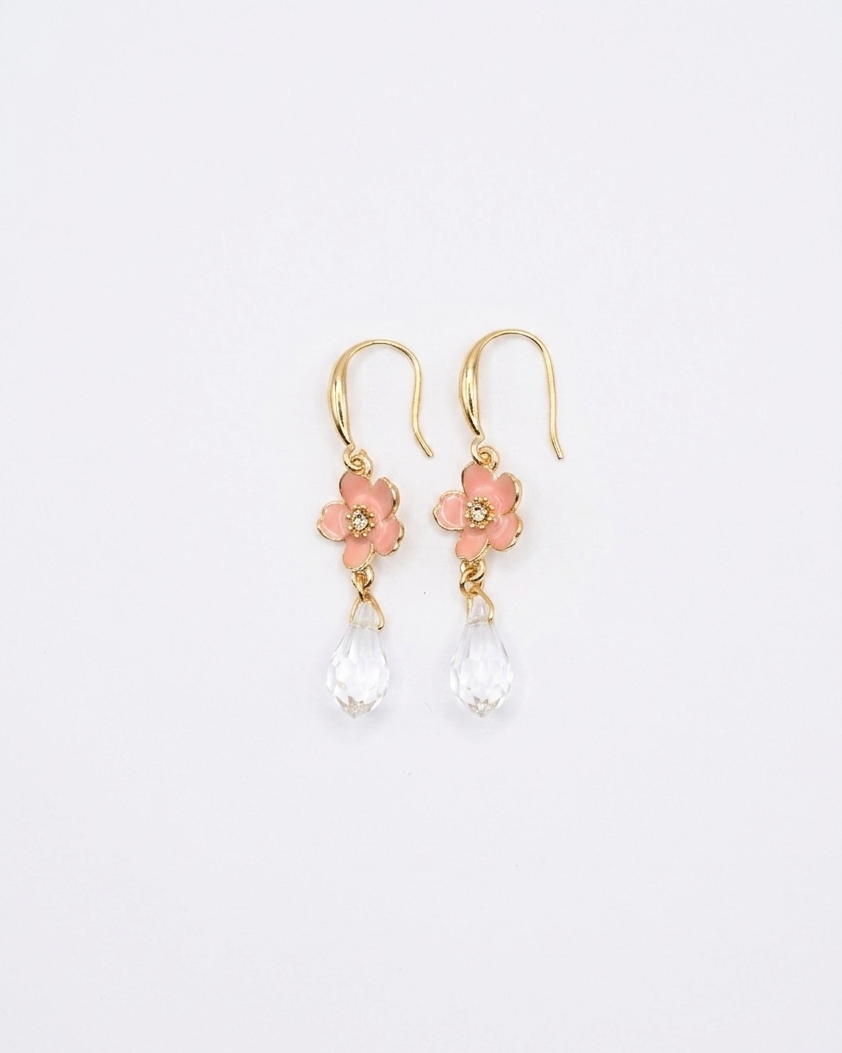 Pair of gold earrings with pink floral elements and clear beads on a light gray background