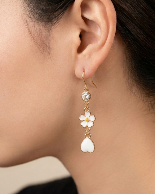 Close up of a model wearing an earring with white sakura flower and petal charms alongside crystal.