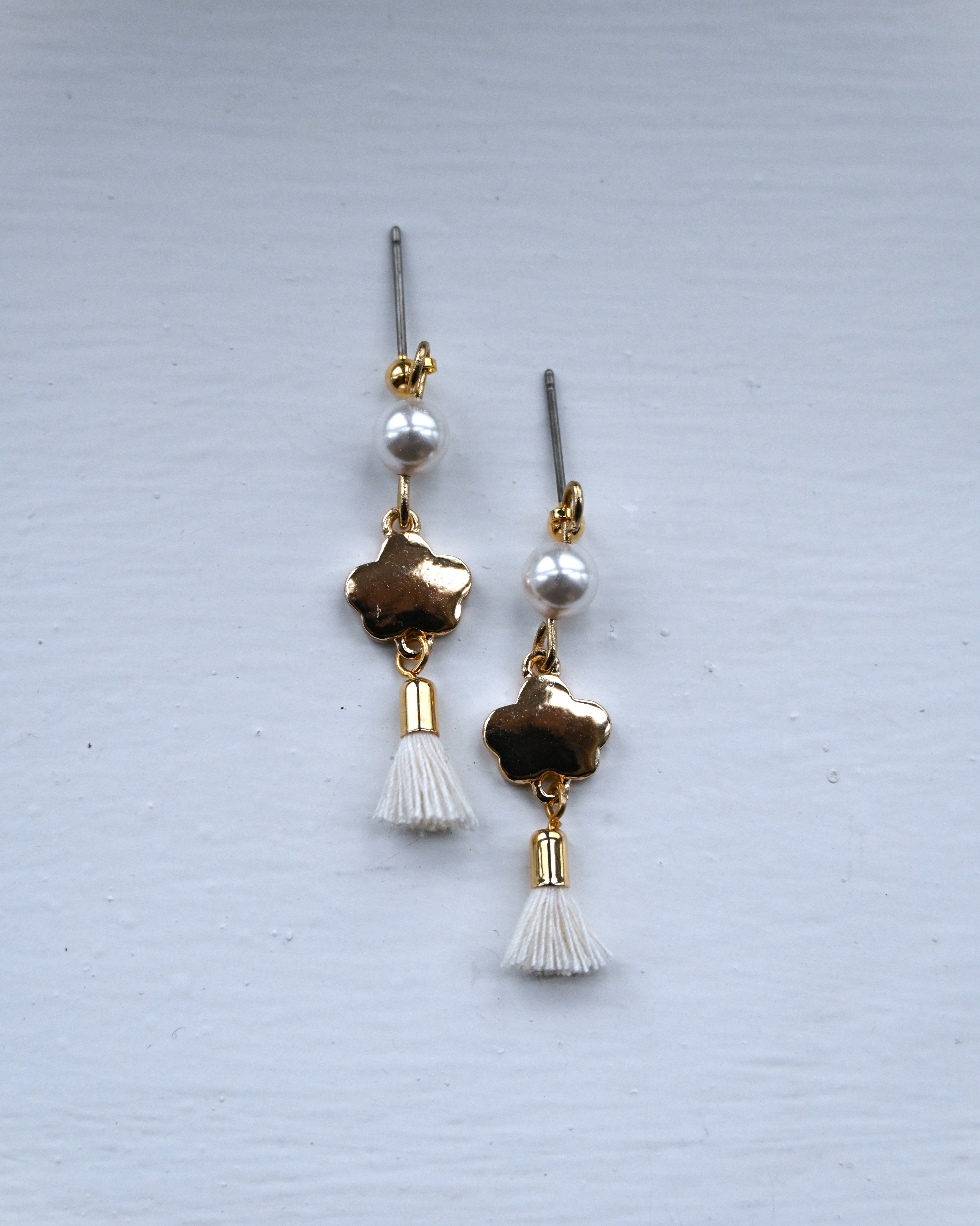 Backside of the earring with gold plating and white pearl and tussel.